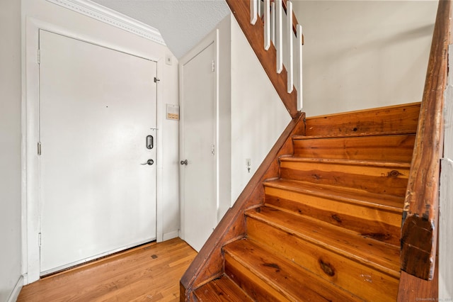 stairs featuring a textured ceiling and wood finished floors