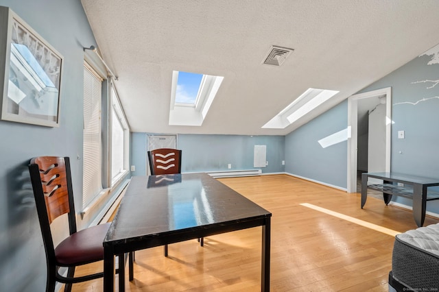 bonus room with wood finished floors, visible vents, vaulted ceiling with skylight, a textured ceiling, and baseboard heating