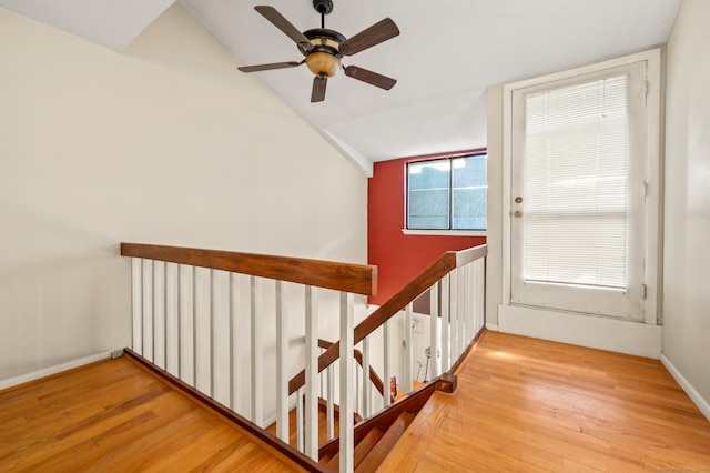 stairway with baseboards, lofted ceiling, and wood finished floors