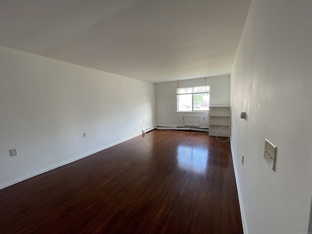 unfurnished room with a baseboard heating unit, baseboards, and dark wood finished floors