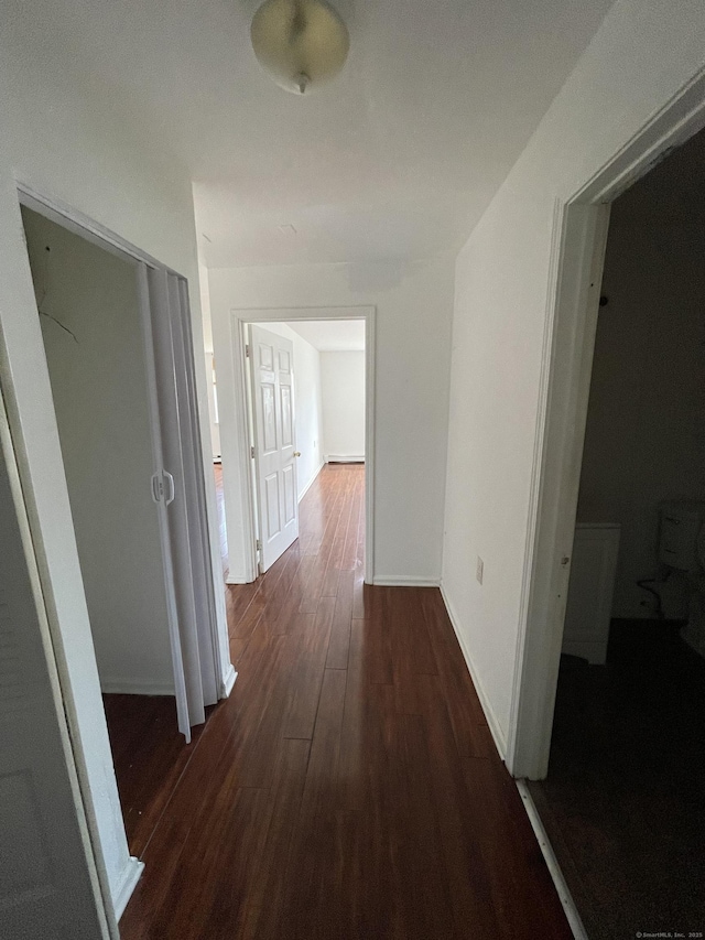 hallway with dark wood finished floors and baseboards