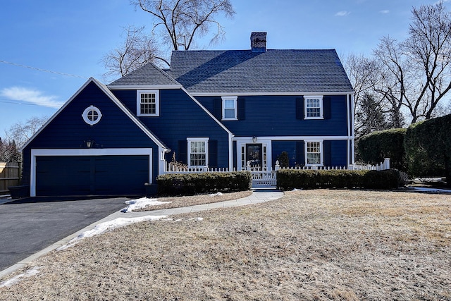 view of front of property with driveway, a shingled roof, and a chimney