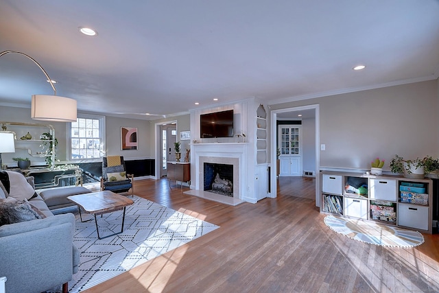 living room featuring crown molding, a fireplace, and wood finished floors