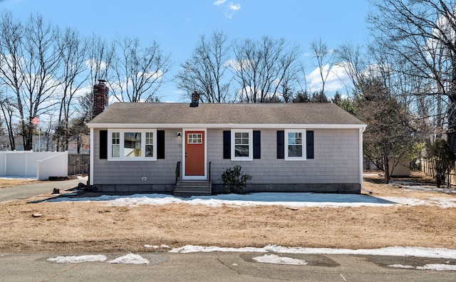 view of front of property featuring a shingled roof, entry steps, fence, and a chimney