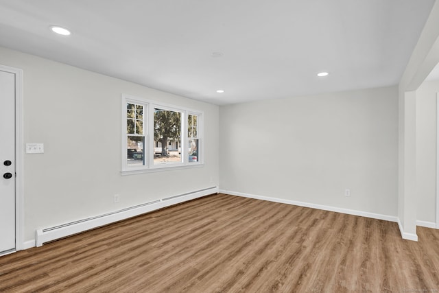 empty room with baseboards, a baseboard heating unit, wood finished floors, and recessed lighting