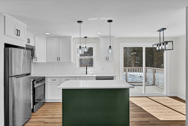 kitchen with light wood finished floors, light countertops, backsplash, appliances with stainless steel finishes, and a sink