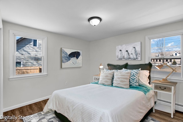 bedroom with a baseboard heating unit, baseboards, and wood finished floors