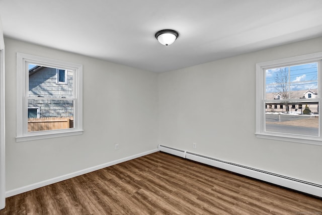 empty room with baseboards, baseboard heating, and wood finished floors