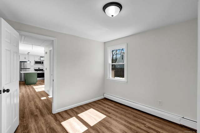 unfurnished room featuring attic access, a baseboard radiator, baseboards, and wood finished floors