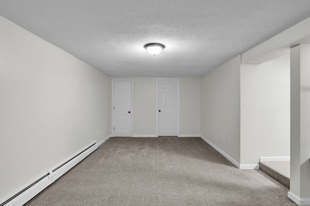 carpeted empty room featuring a textured ceiling, a baseboard radiator, and baseboards