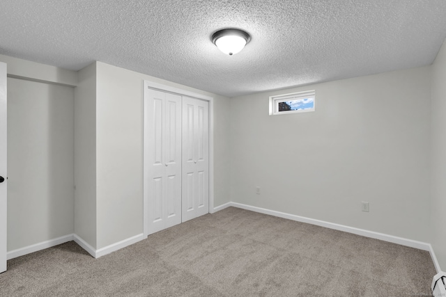 unfurnished bedroom with carpet floors, a closet, a textured ceiling, and baseboards