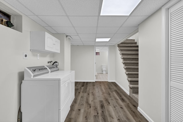 laundry area with baseboards, cabinet space, washing machine and clothes dryer, and wood finished floors