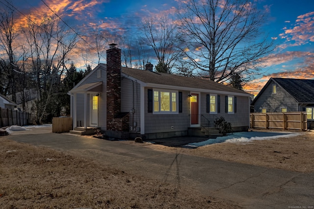 ranch-style house featuring a chimney and fence