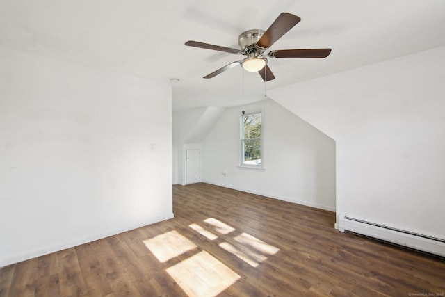 additional living space with ceiling fan, a baseboard heating unit, baseboards, vaulted ceiling, and dark wood finished floors