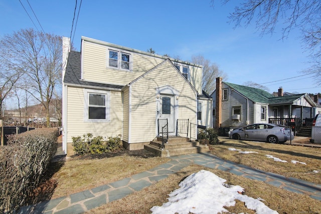 view of front of house with a shingled roof and a chimney