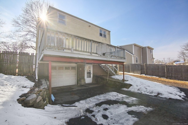 snow covered property featuring a garage, fence, and stairs