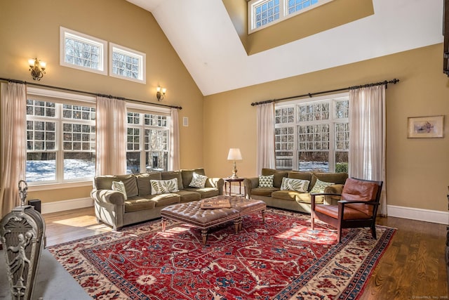 living area with high vaulted ceiling, wood finished floors, and baseboards