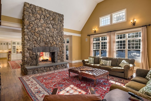 living area featuring high vaulted ceiling, hardwood / wood-style floors, a fireplace, and baseboards