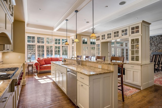 kitchen with dark wood finished floors, appliances with stainless steel finishes, a sink, beamed ceiling, and a kitchen breakfast bar