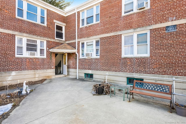 entrance to property featuring cooling unit, brick siding, and a patio