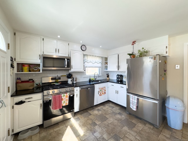 kitchen featuring a sink, white cabinetry, appliances with stainless steel finishes, open shelves, and dark countertops