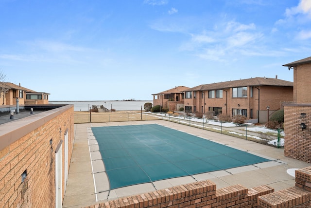 view of swimming pool with a water view and fence