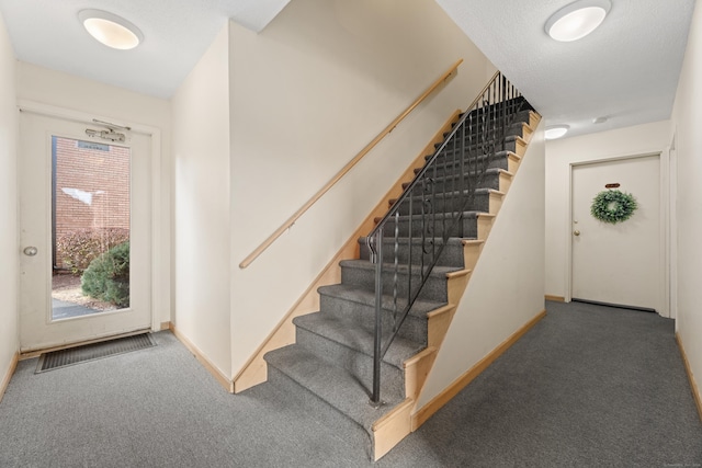 stairway featuring visible vents, baseboards, and carpet flooring