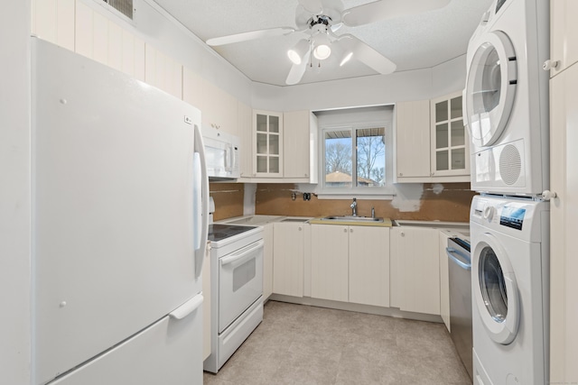 kitchen with stacked washer and dryer, white appliances, glass insert cabinets, and a sink