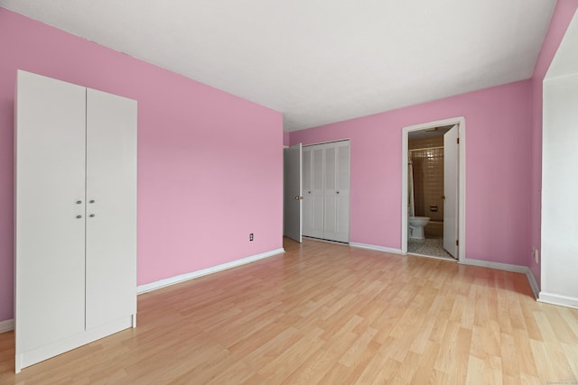 unfurnished bedroom with multiple closets, light wood-type flooring, connected bathroom, and baseboards