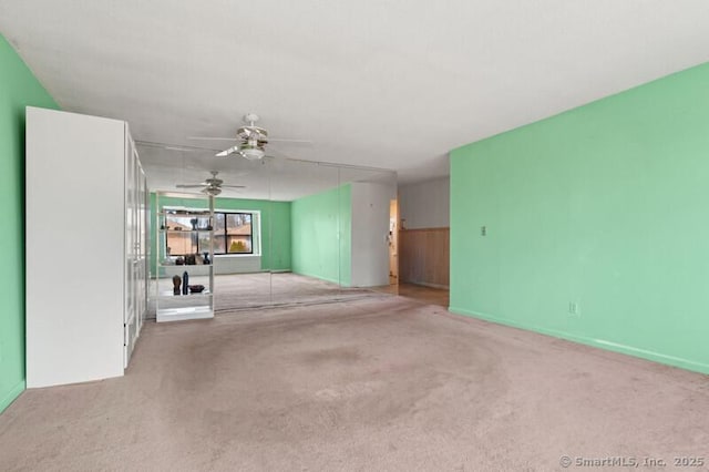 unfurnished living room featuring a ceiling fan and light colored carpet