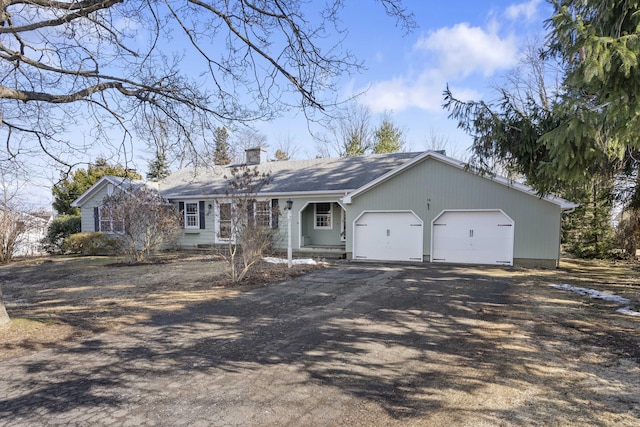 single story home featuring driveway, a chimney, and an attached garage