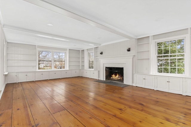 unfurnished living room featuring built in shelves, hardwood / wood-style flooring, a brick fireplace, and beam ceiling