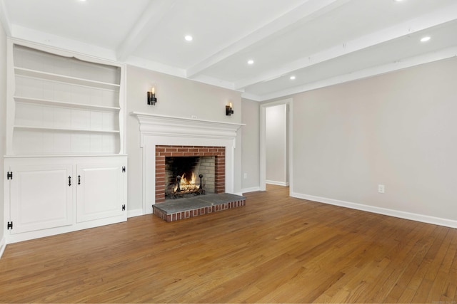 unfurnished living room featuring recessed lighting, hardwood / wood-style floors, a brick fireplace, beamed ceiling, and baseboards