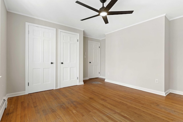 unfurnished bedroom featuring baseboards, hardwood / wood-style floors, and crown molding