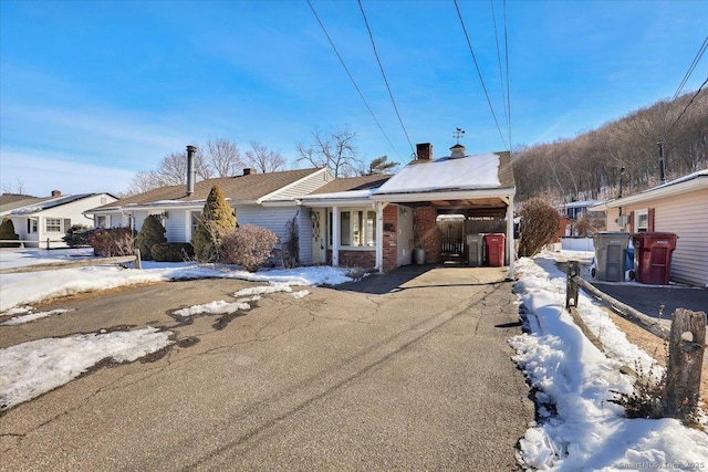 ranch-style home with aphalt driveway, an attached carport, and brick siding