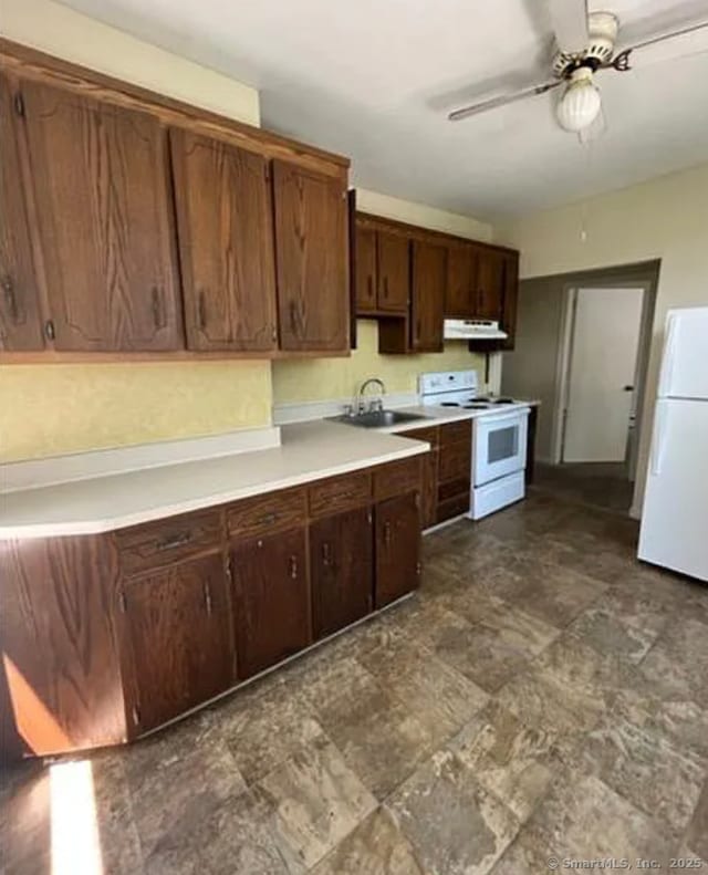 kitchen featuring white appliances, ceiling fan, light countertops, under cabinet range hood, and a sink