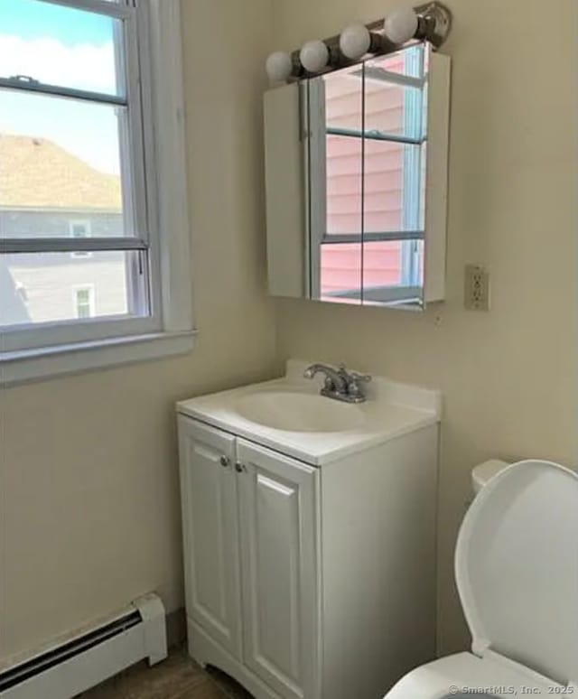 half bathroom featuring baseboard heating, vanity, and a wealth of natural light