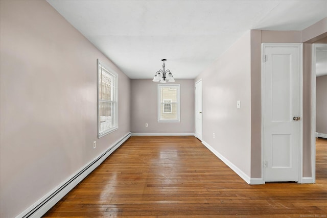 interior space featuring a chandelier, baseboard heating, wood finished floors, and baseboards