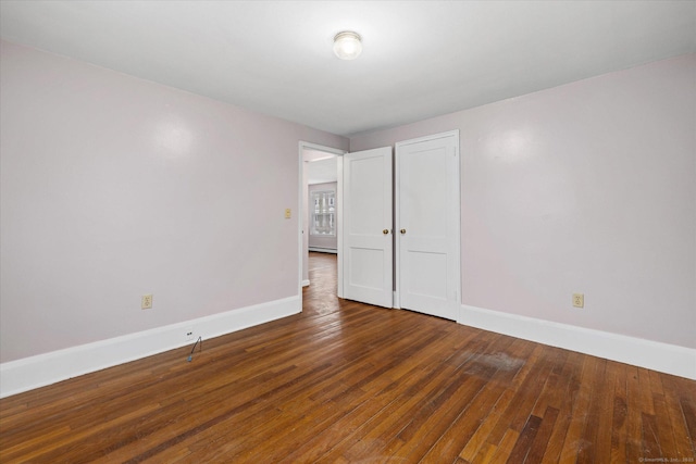 empty room with dark wood-style floors and baseboards