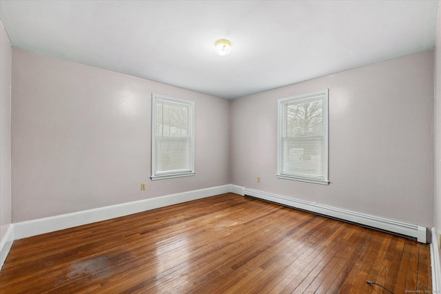 unfurnished room featuring a baseboard heating unit, wood finished floors, and baseboards