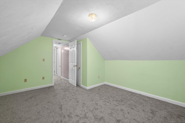 additional living space with carpet, vaulted ceiling, a textured ceiling, and baseboards