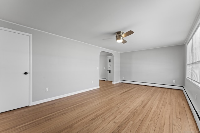 empty room with arched walkways, baseboard heating, a ceiling fan, and light wood-style floors