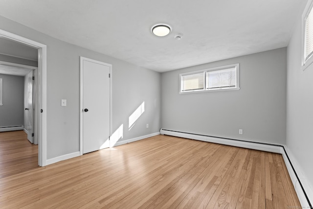 unfurnished room with a baseboard radiator, light wood-style flooring, and baseboards