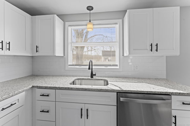 kitchen with decorative backsplash, stainless steel dishwasher, white cabinetry, a sink, and light stone countertops