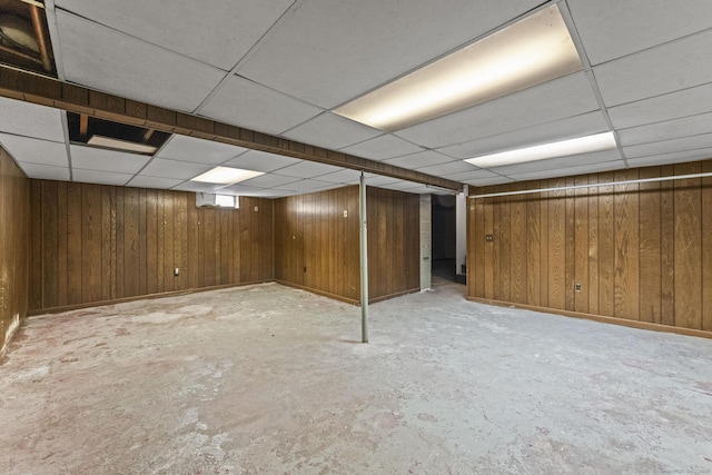 finished basement featuring a paneled ceiling and wooden walls