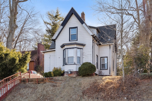 view of front of house with roof with shingles, fence, and a chimney