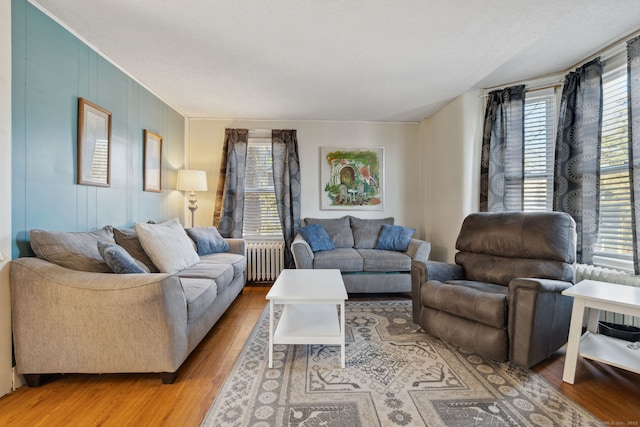 living area with a healthy amount of sunlight, light wood-style flooring, and radiator heating unit