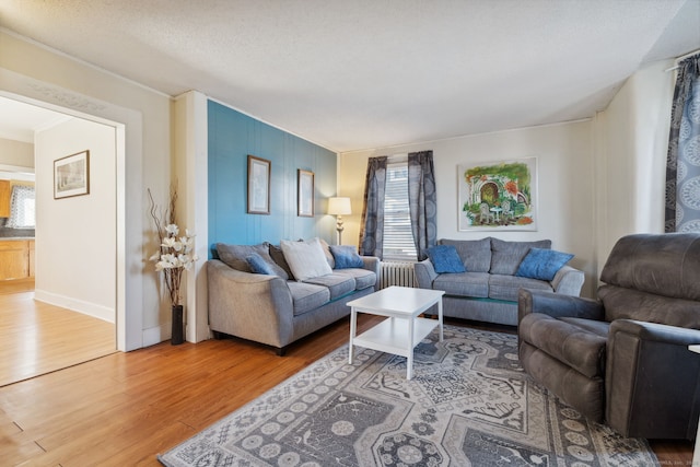 living area featuring a textured ceiling, baseboards, and wood finished floors