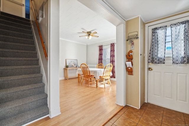 entryway featuring light wood finished floors, ceiling fan, stairs, and ornamental molding