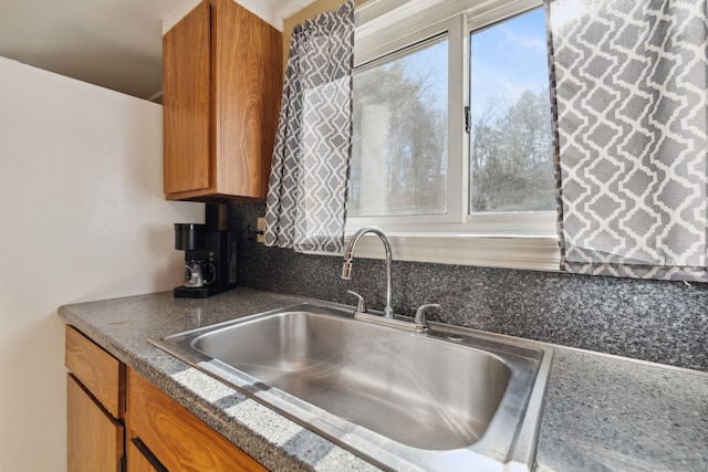 kitchen with brown cabinetry, a wealth of natural light, and a sink